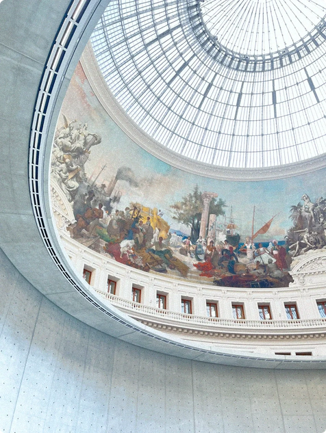 Kuppelgewölbe mit Glasdach und Wandfresken, die historische Szenen und Figuren der Antike darstellen.