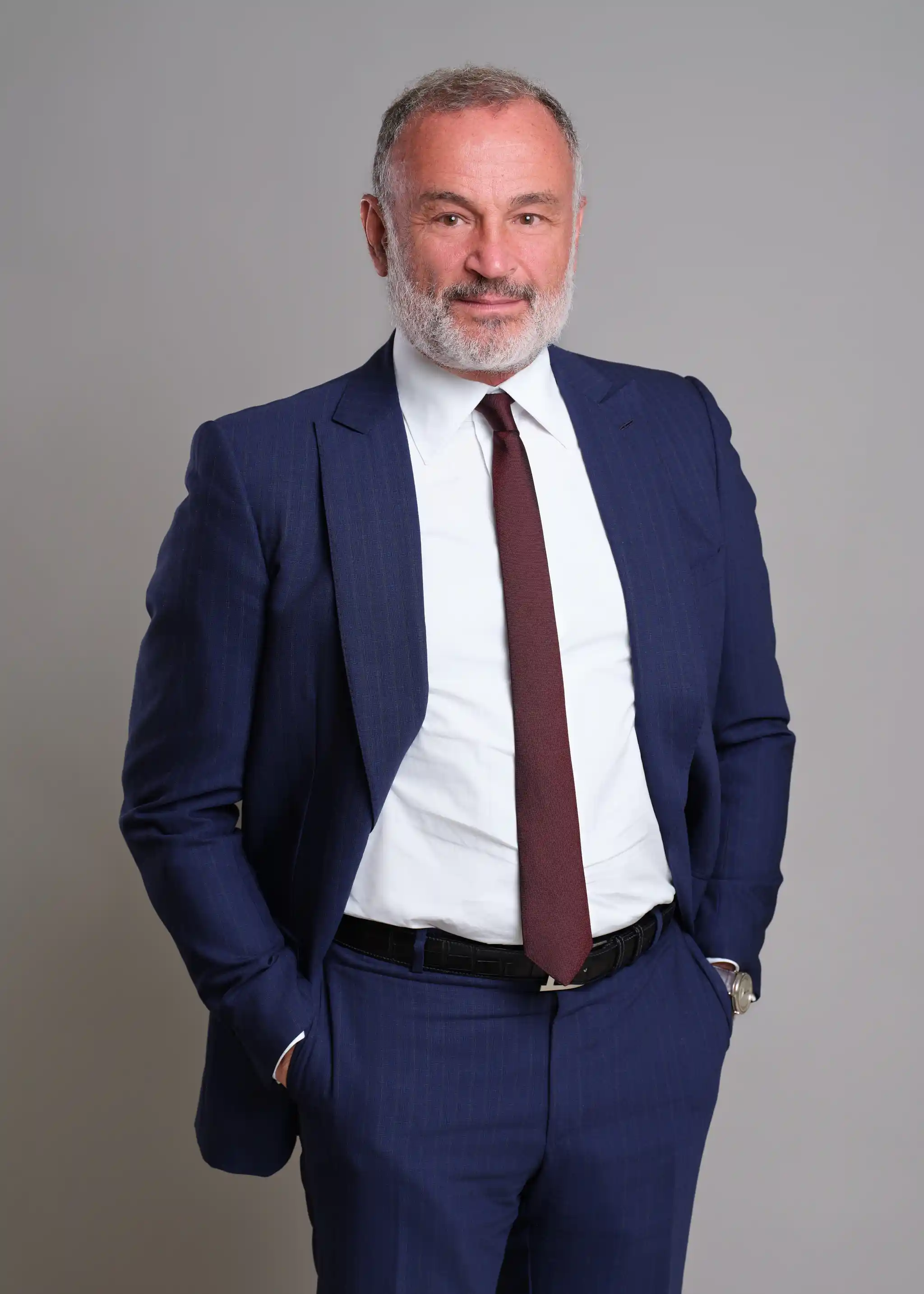 A middle-aged man with a gray beard, wearing a white shirt and a blue blazer, looking at the camera.