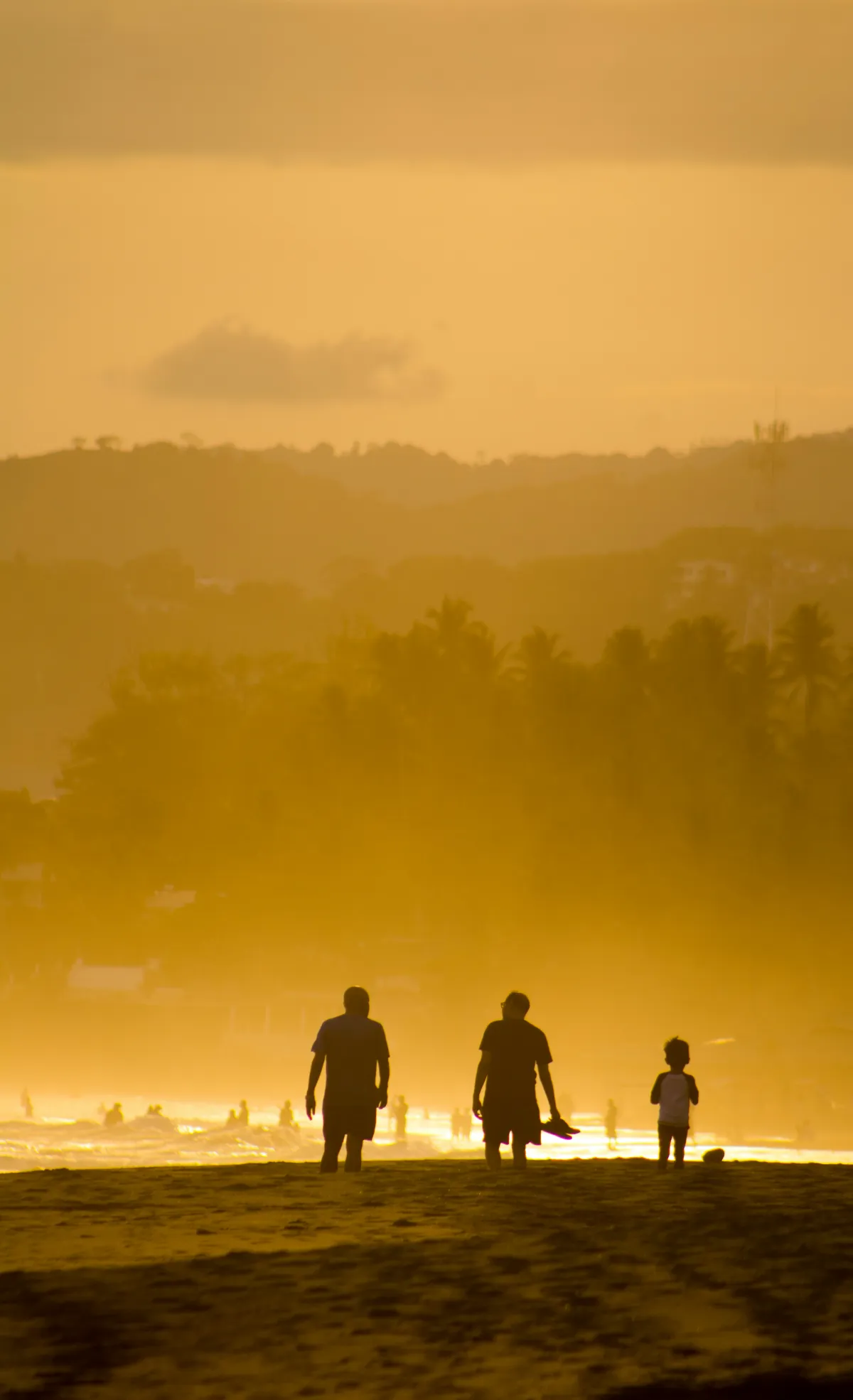 Famille marchant sur une plage au coucher du soleil, illustrant la transmission patrimoniale entre générations