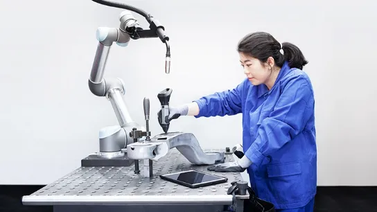 Opératrice utilisant le stylet de programmation Wandelbots pour guider un bras robotisé industriel