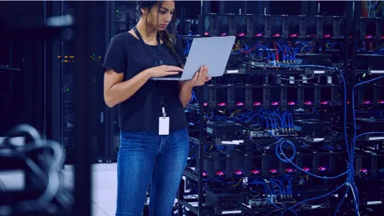 Technicienne réseau travaillant sur ordinateur portable devant des baies de serveurs dans un centre de données Vitaprotech