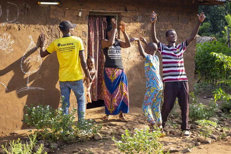 Femmes et enfants africains dansant devant maison