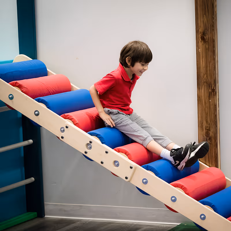A boy enjoying a ramp in the gym space at North Shore Pediatric Therapy