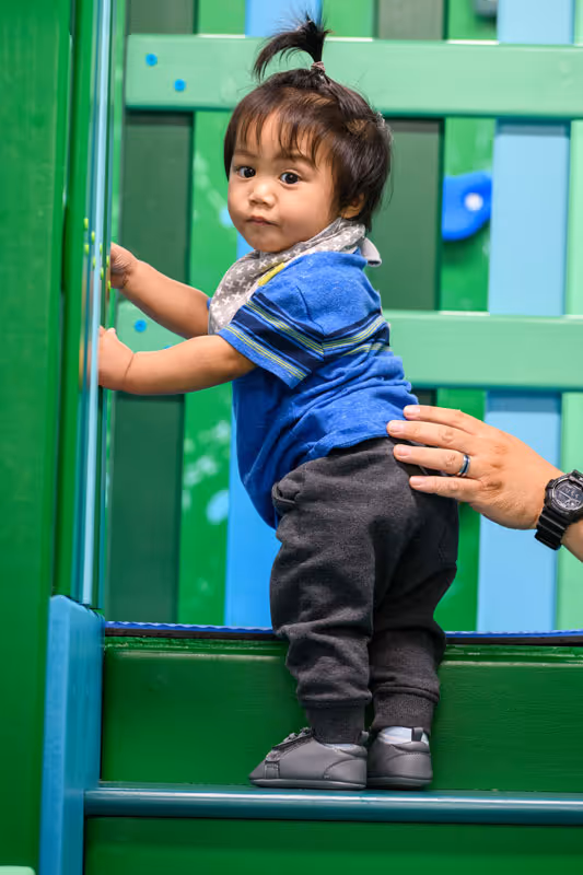 Toddler climbing on play gym at therapy center