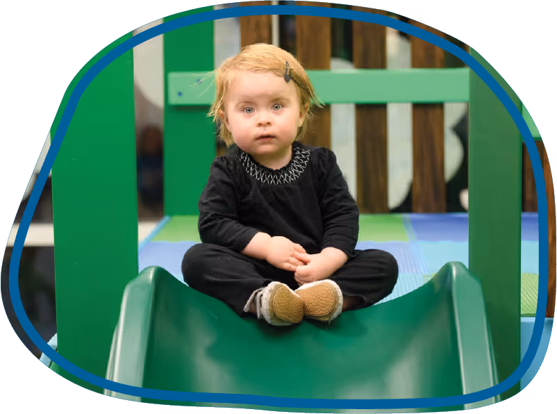 Child sitting on a slide in the therapy gym during an ABA therapy session