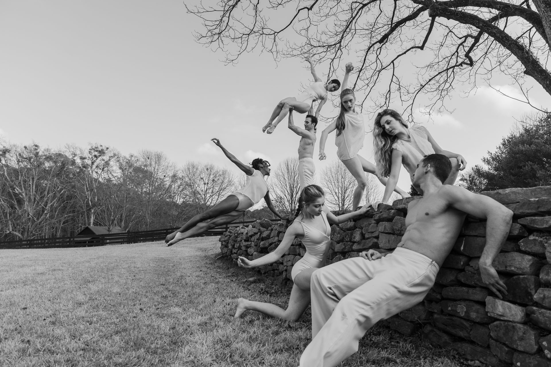 Dancers pose along outdoor rock wall