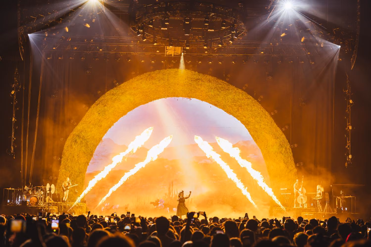 Melanie Martinez performing with pyro shooting overhead as a large crowd watches