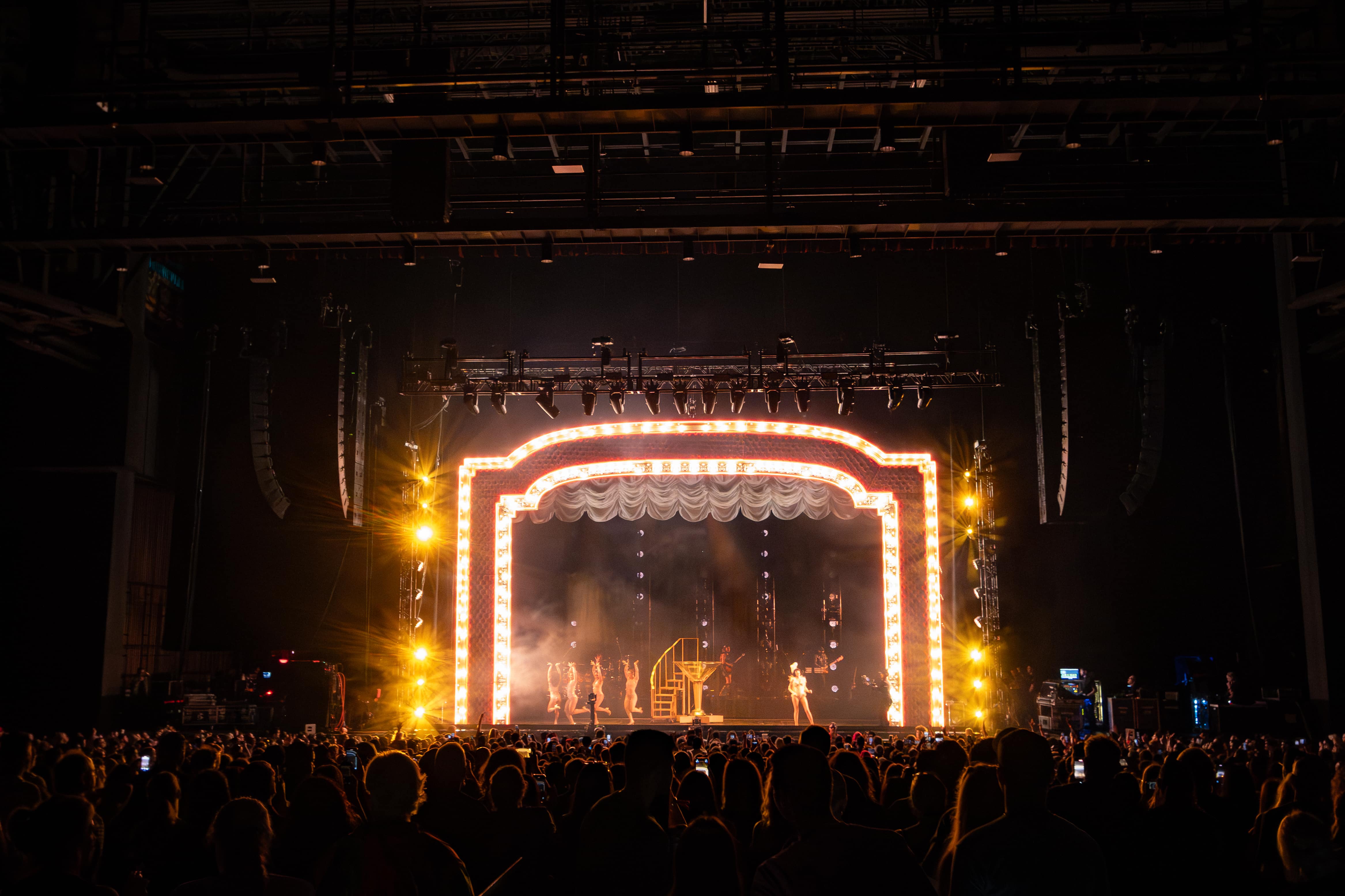Halsey performs in front of a golden false proscenium in a flapper's attire, standing next to a giant fake martini glass.