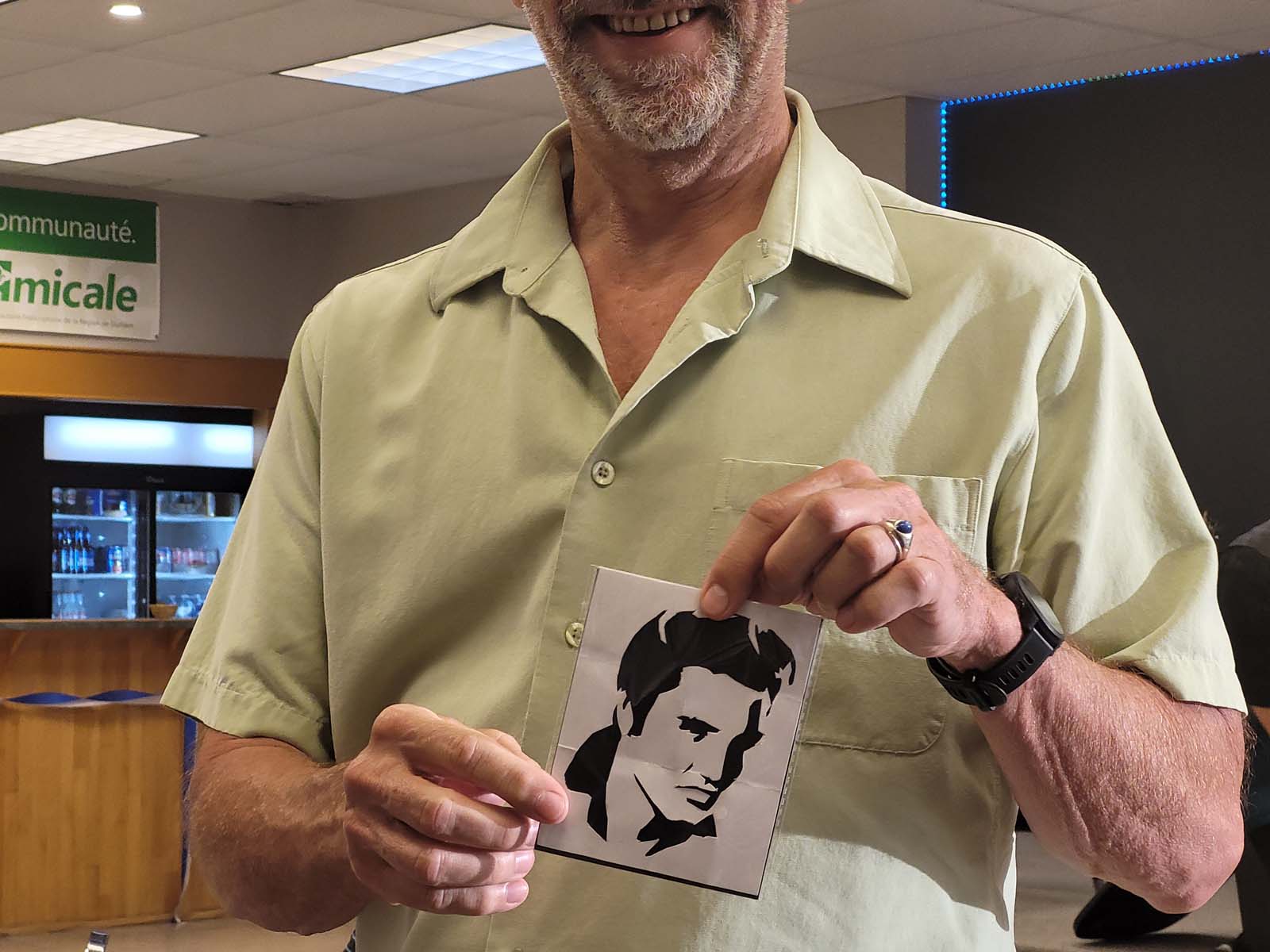 Gros plan sur un participant tenant une carte avec un portrait mystérieux en noir et blanc révélé pendant un tour de magie.