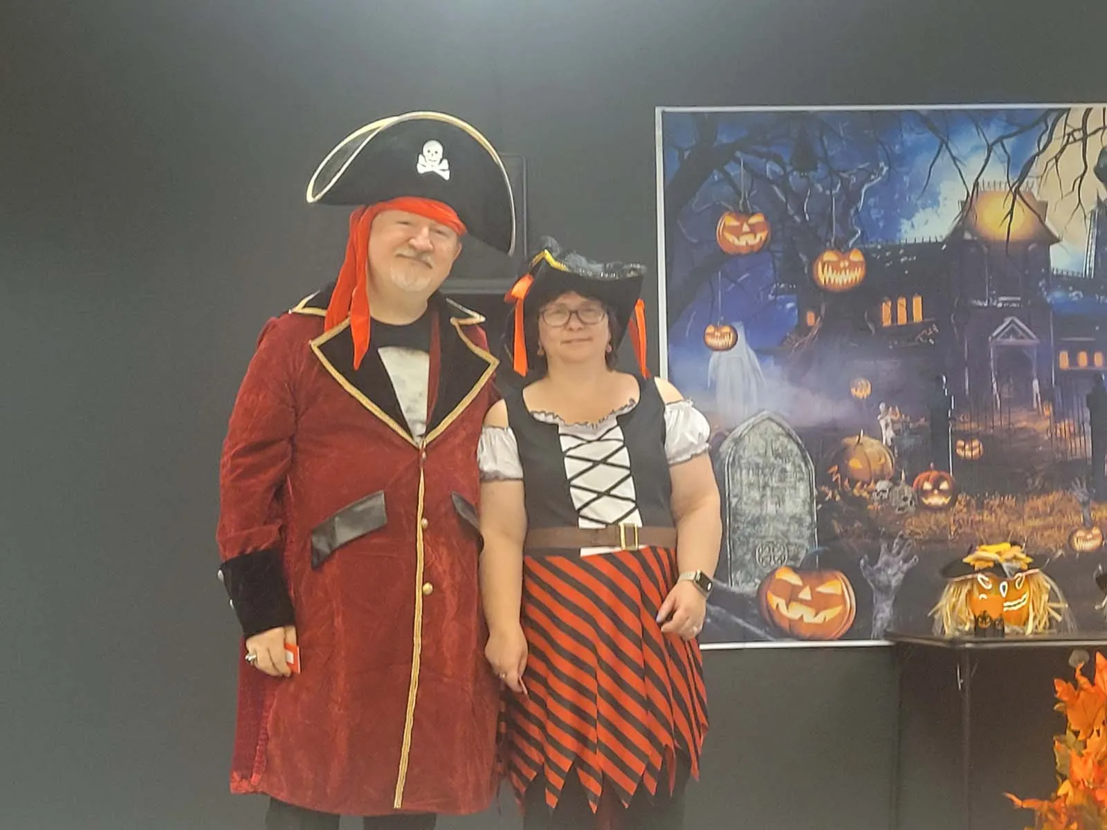Un homme et une femme déguisés en pirates posent ensemble devant le décor du manoir hanté. Leur costume rouge et noir rappelle l’esprit festif et théâtral de la soirée.