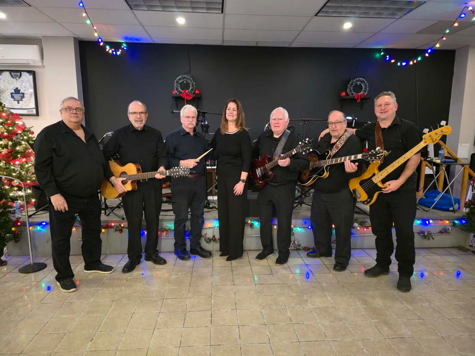 Groupe de musiciens membres de L’Amicale posant ensemble, instruments en main, sur la scène décorée pour la soirée.
