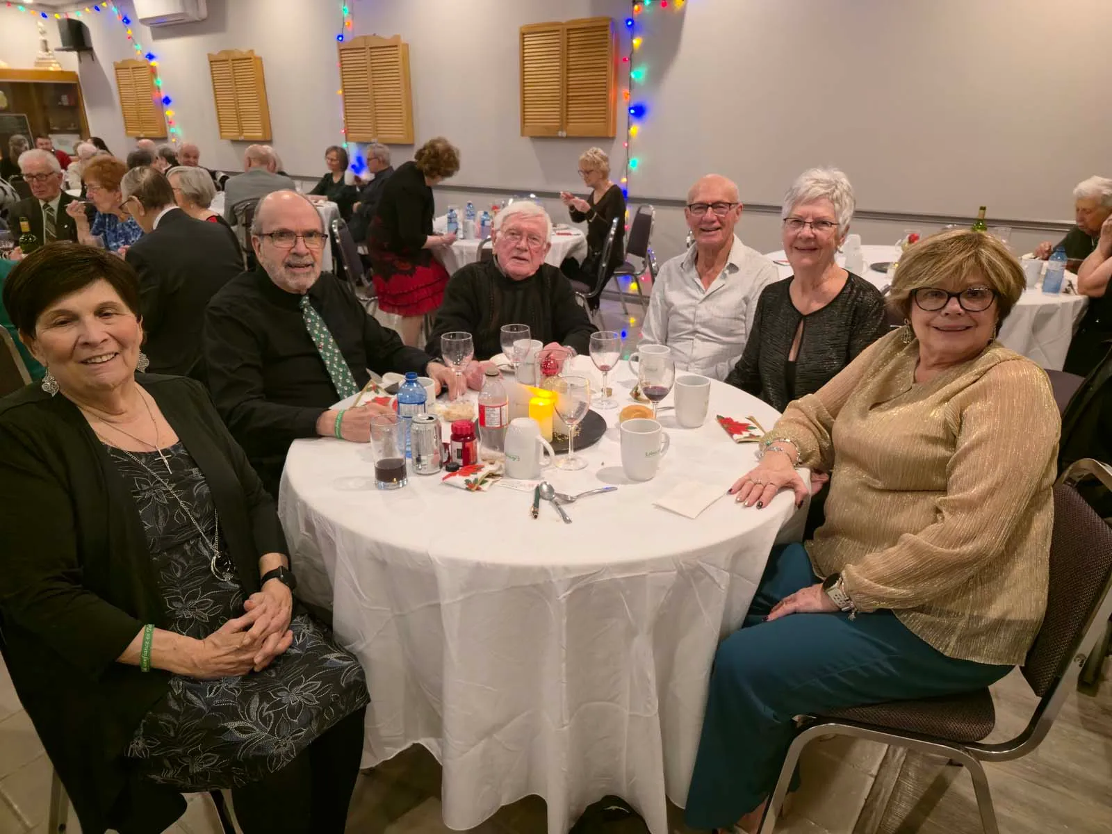 Membres de L’Amicale réunis autour d’une table, partageant un moment convivial avec boissons et dessert pendant la soirée.