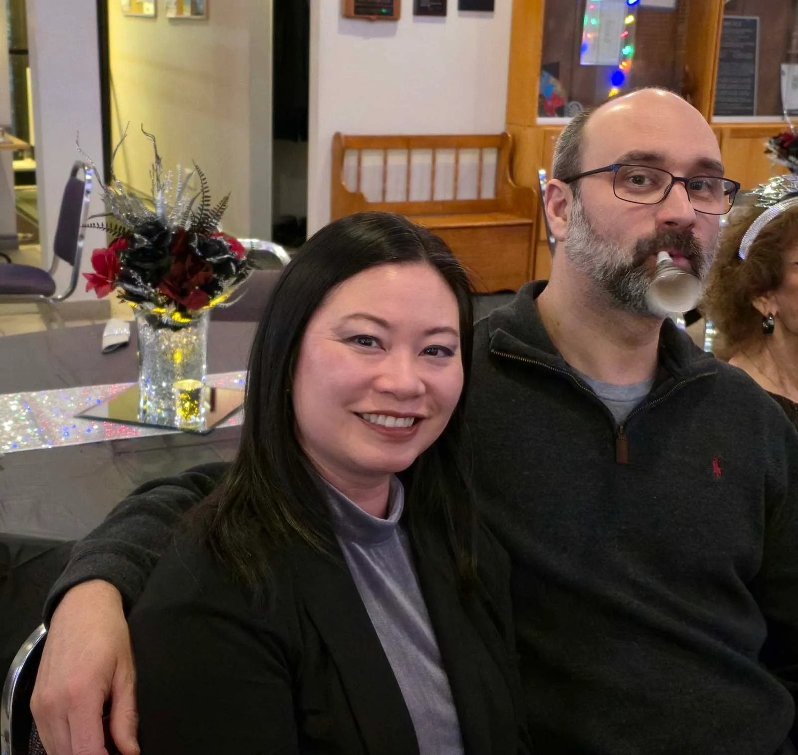 Deux membres de L’Amicale posant ensemble, souriants et détendus, assis à une table décorée pour la soirée.