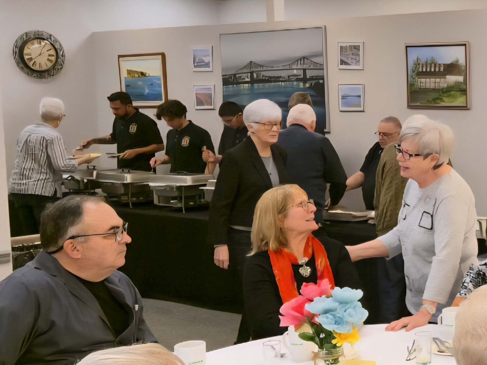 Membres de L’Amicale faisant la file au buffet, servis par des bénévoles, pendant le repas communautaire.