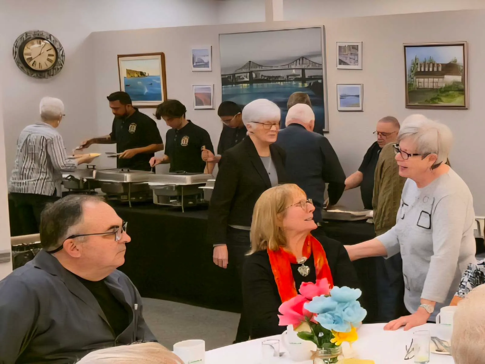 Membres de L’Amicale faisant la file au buffet, servis par des bénévoles, pendant le repas communautaire.