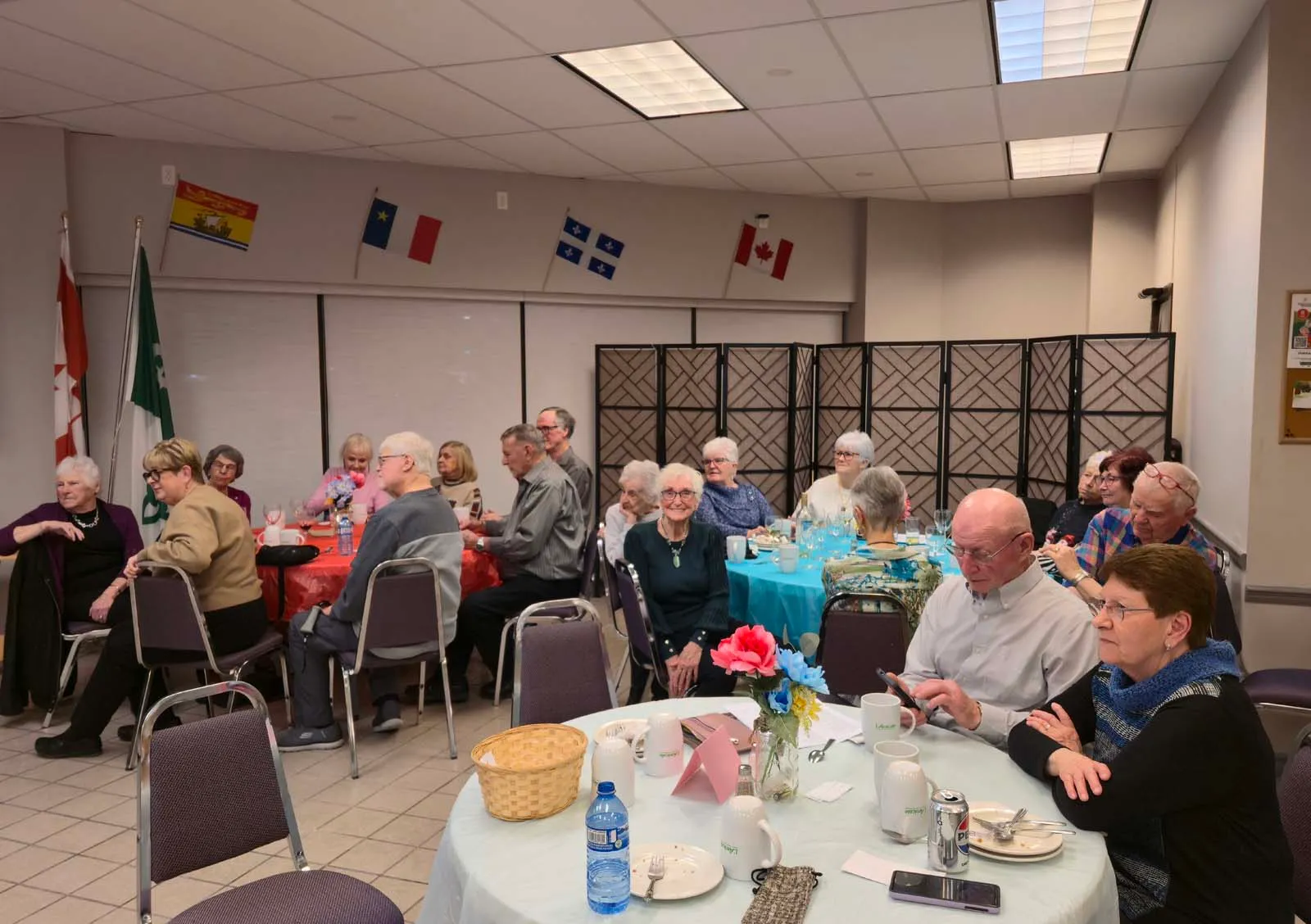 Groupe de membres de L’Amicale assis à une table, écoutant attentivement une présentation ou animation.