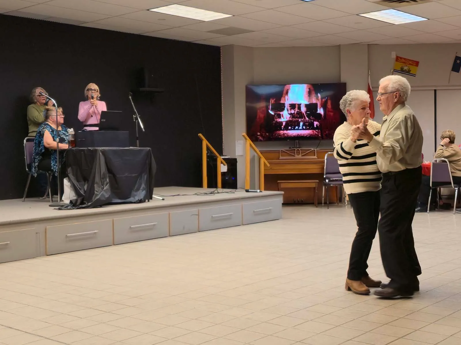 Deux membres de L’Amicale dansant ensemble devant la scène pendant une soirée musicale.