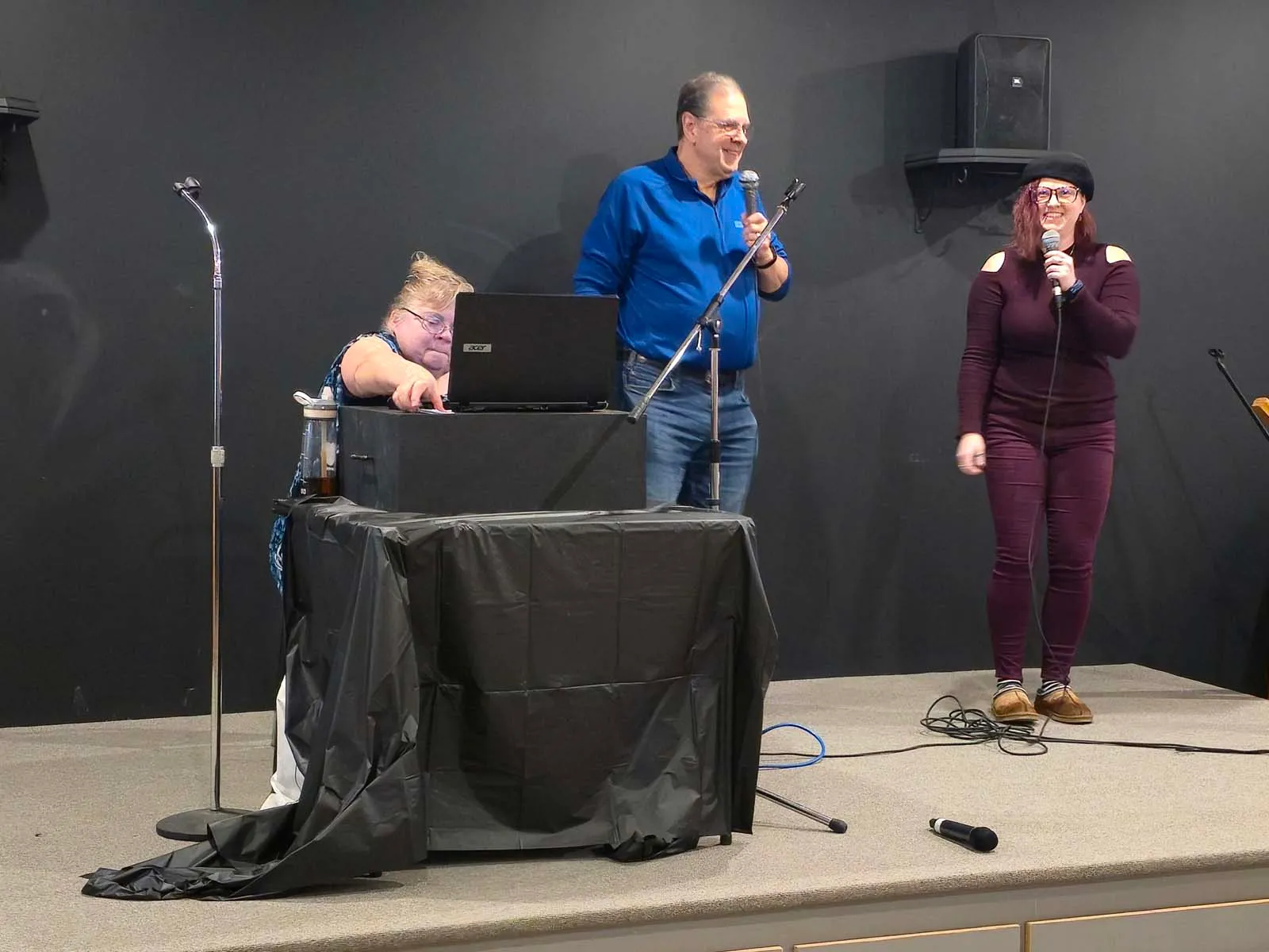 Membres de L’Amicale animant la soirée musicale sur scène, avec chant et accompagnement audio.