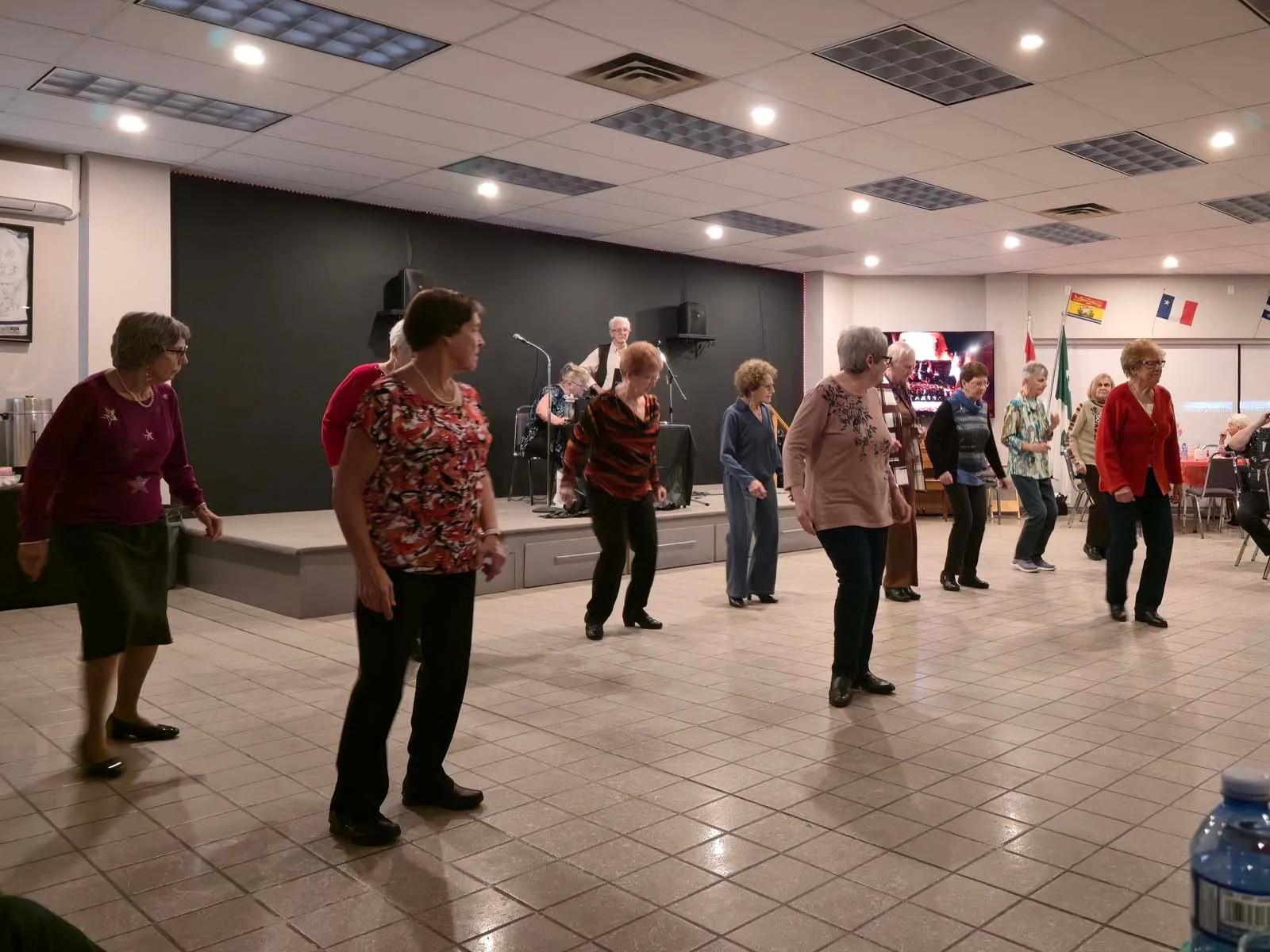 Des membres de L’Amicale participent à une danse en ligne dans la salle communautaire.