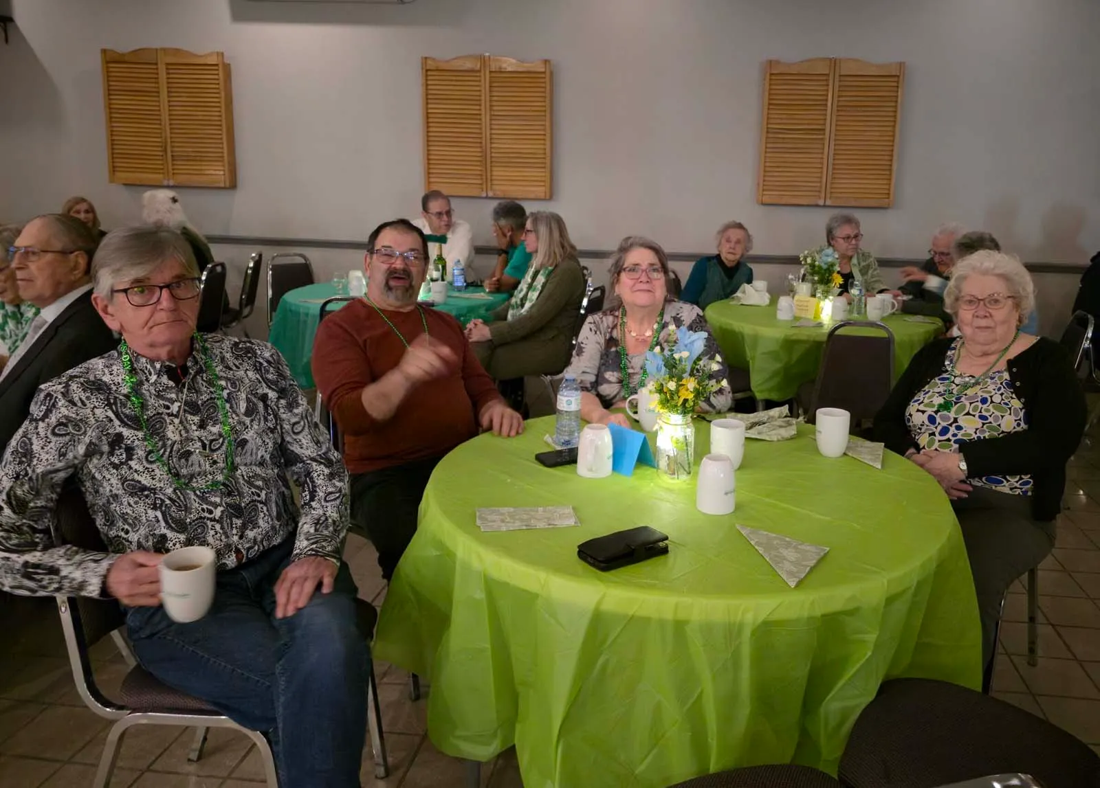 membres d'Amicale assis aux tables décorées pour la Saint-Patrick
