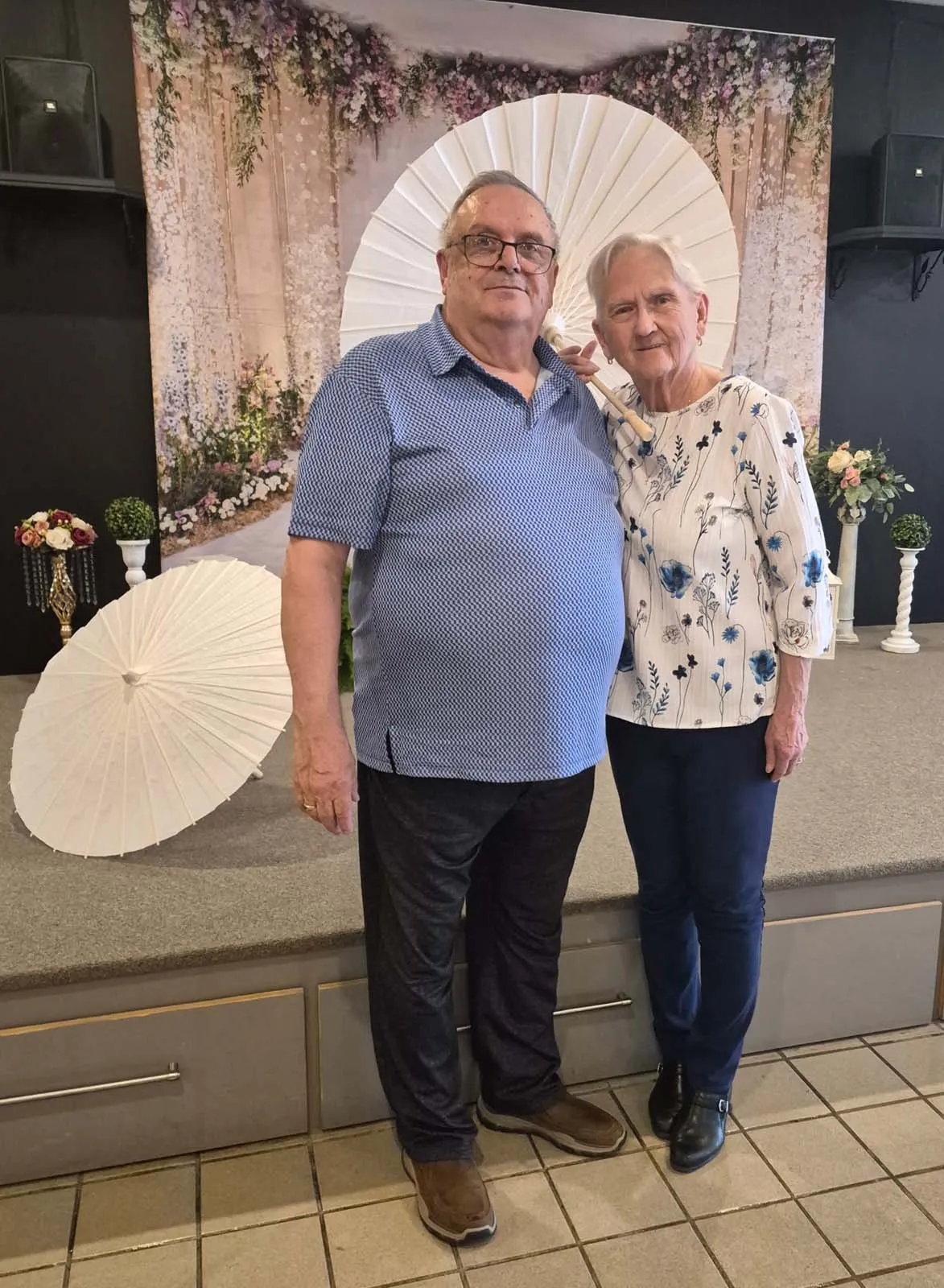 Deux participants posant devant les parasols et le décor fleuri du brunch de la Fête des Mères.