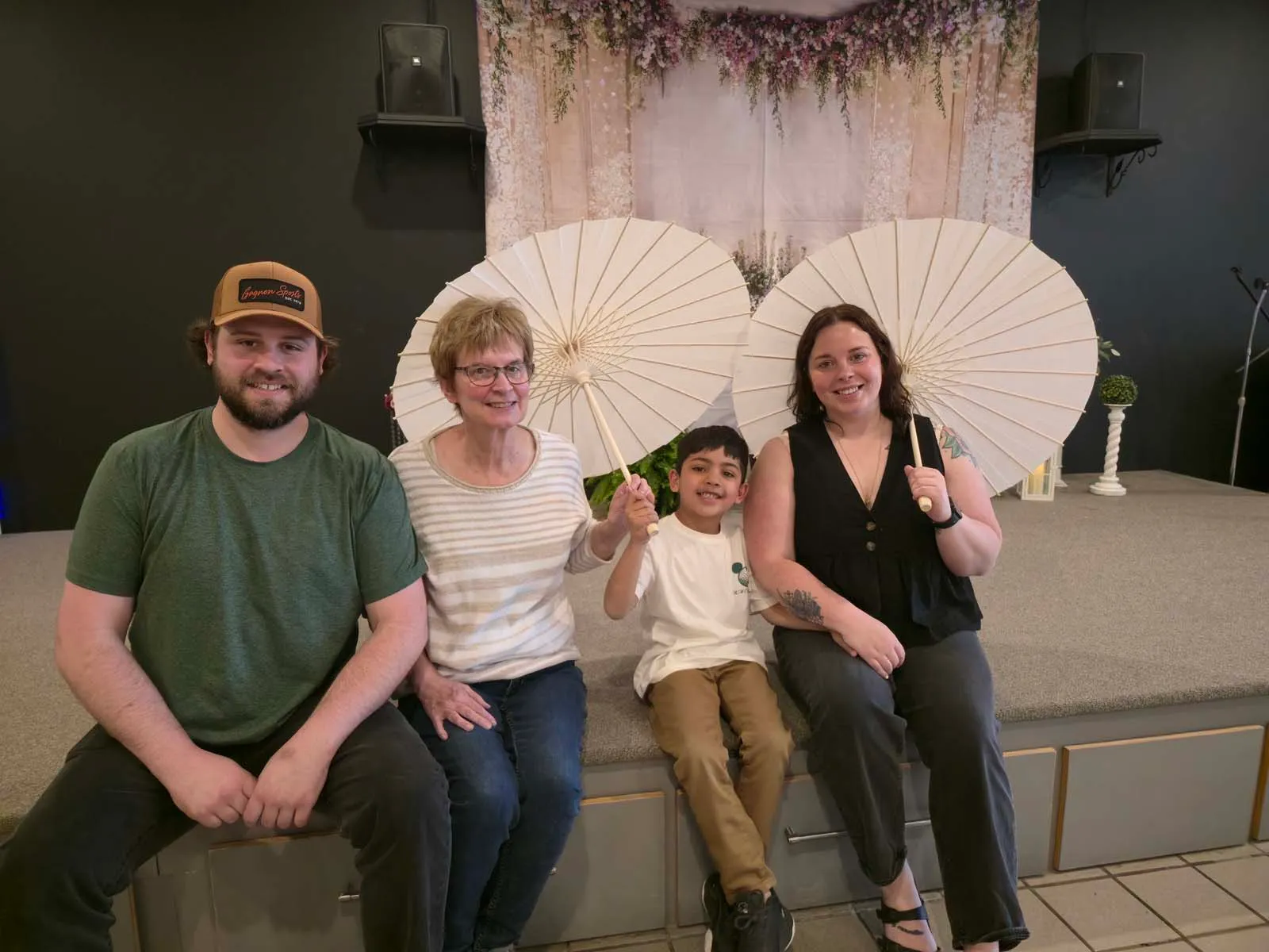 Famille posant devant le décor avec parasols lors du brunch de la Fête des Mères de l’Amicale.