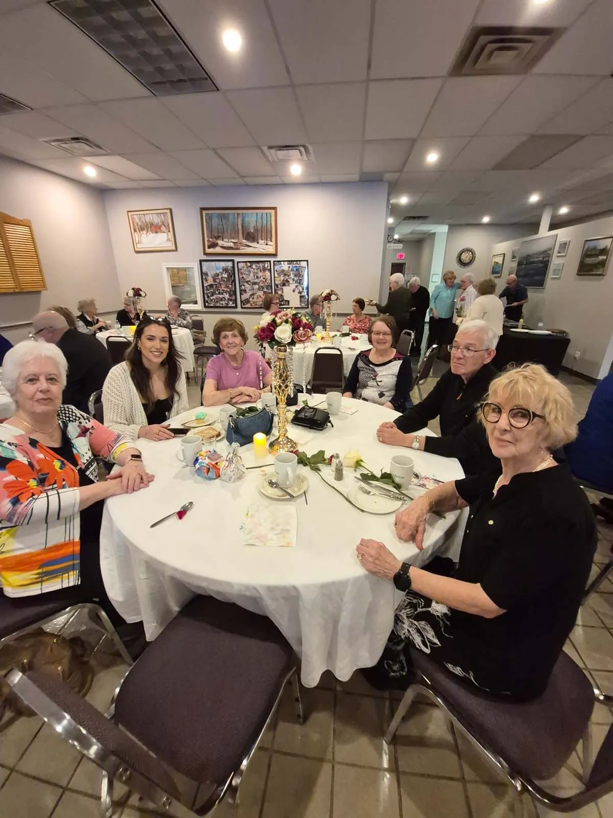 Groupe de participantes souriantes autour d’une table pendant le brunch de la Fête des Mères de l’Amicale.