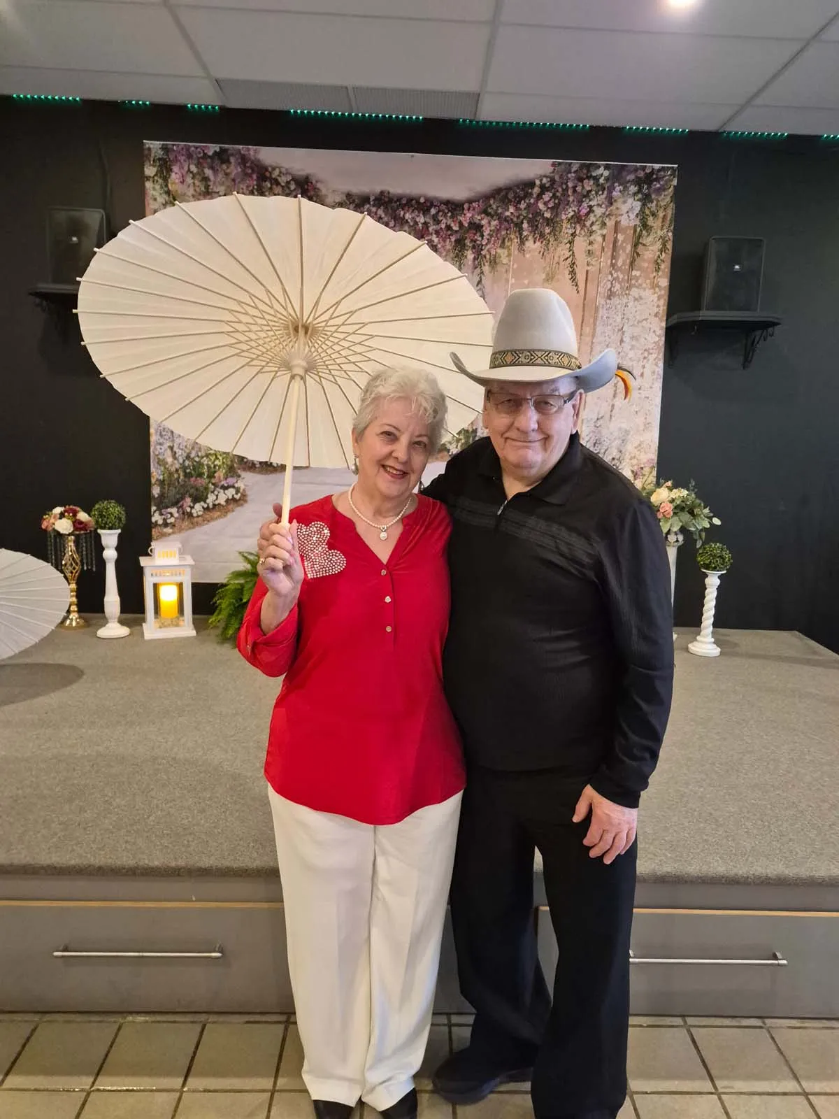 Deux participants posant devant le décor fleuri du brunch de la Fête des Mères de l’Amicale.