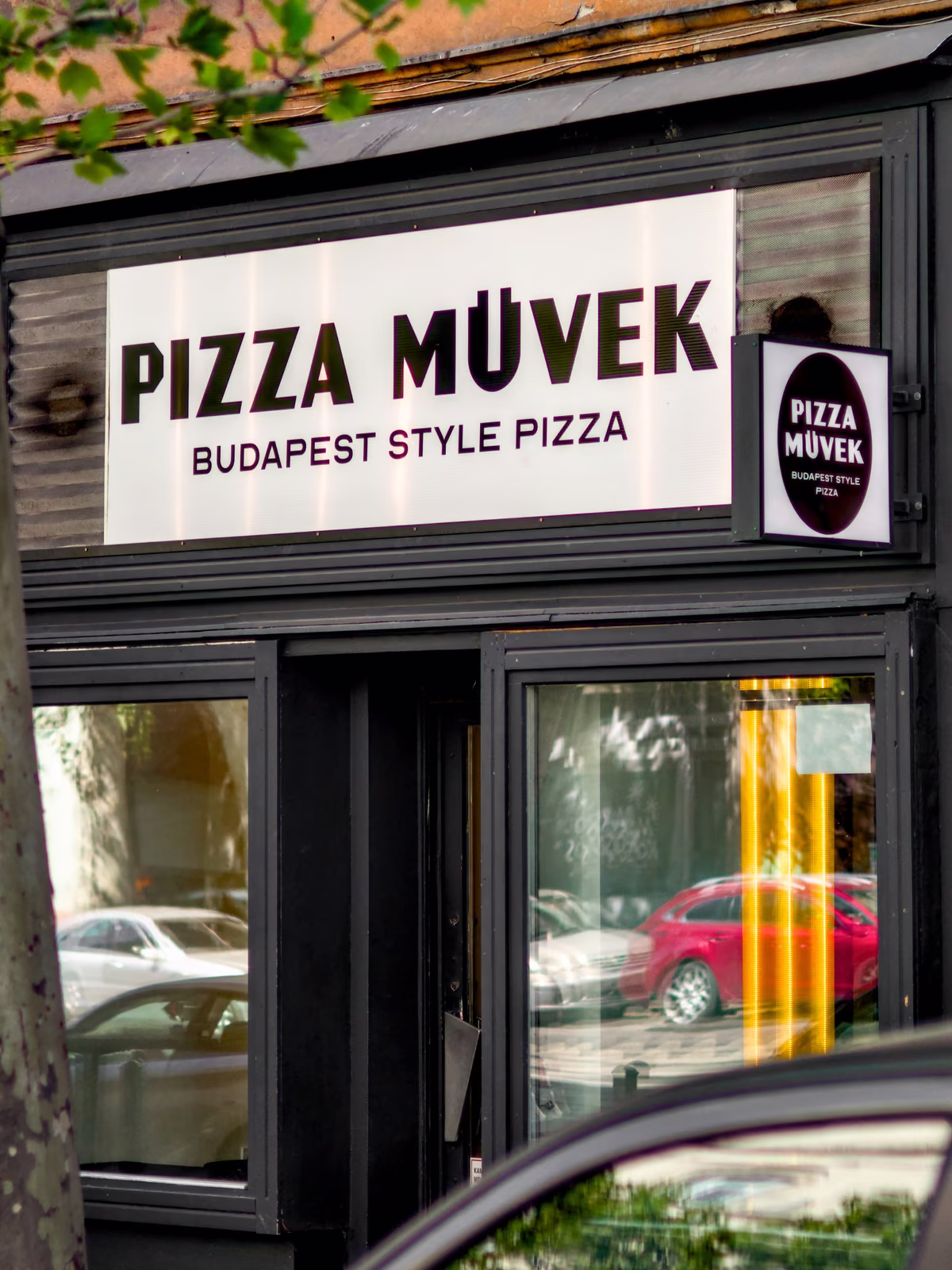 A Pizza Művek üzletportálja a világító logós felirattal a bejárat felett