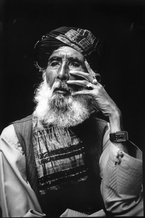 A man in Afghanistan poses for a photo with his hand touching the side of his face.