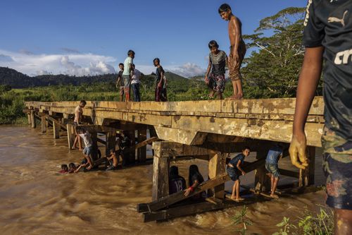 Young people stand on a platform along a river.