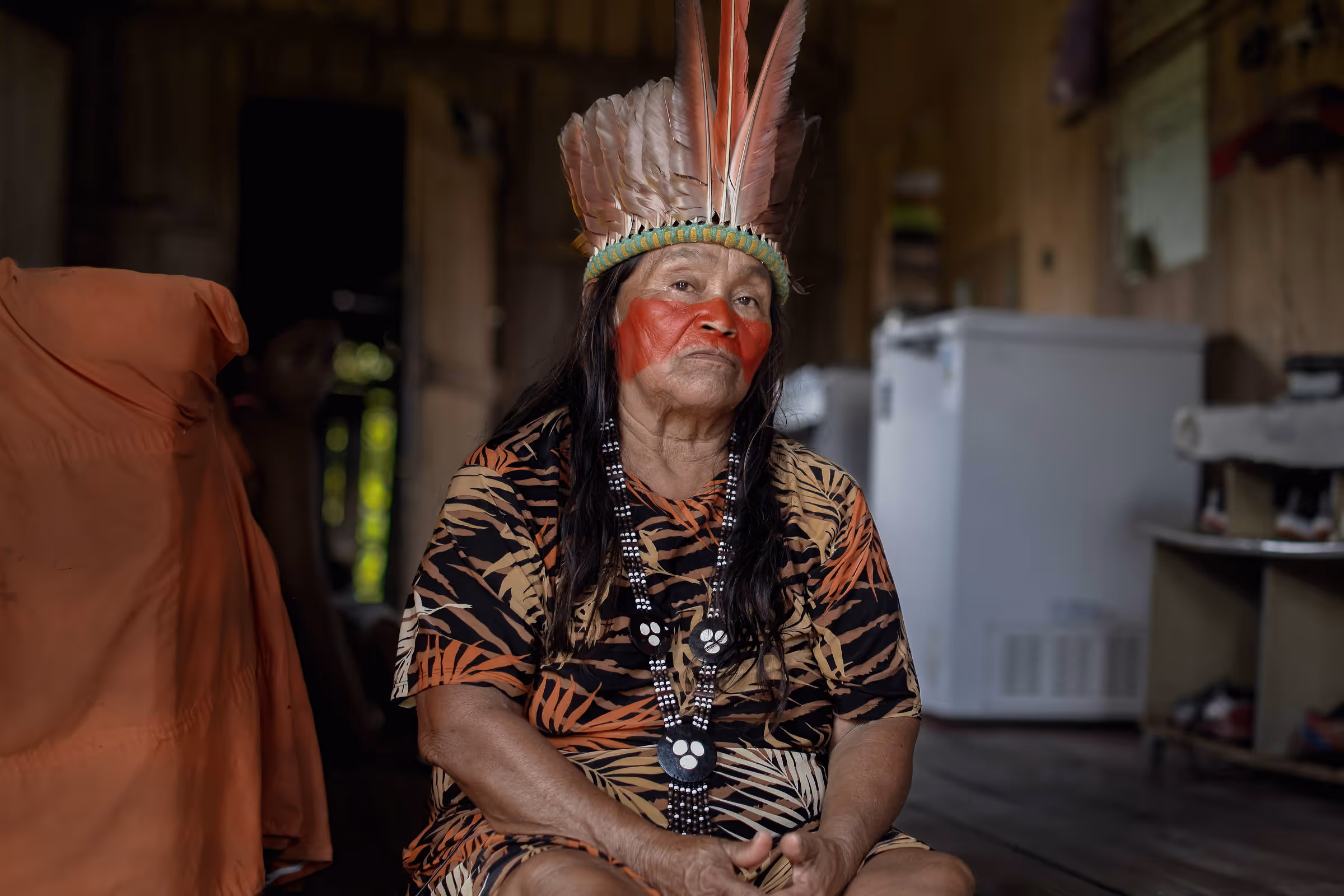 A woman sits solemnly with her hands on her lap.