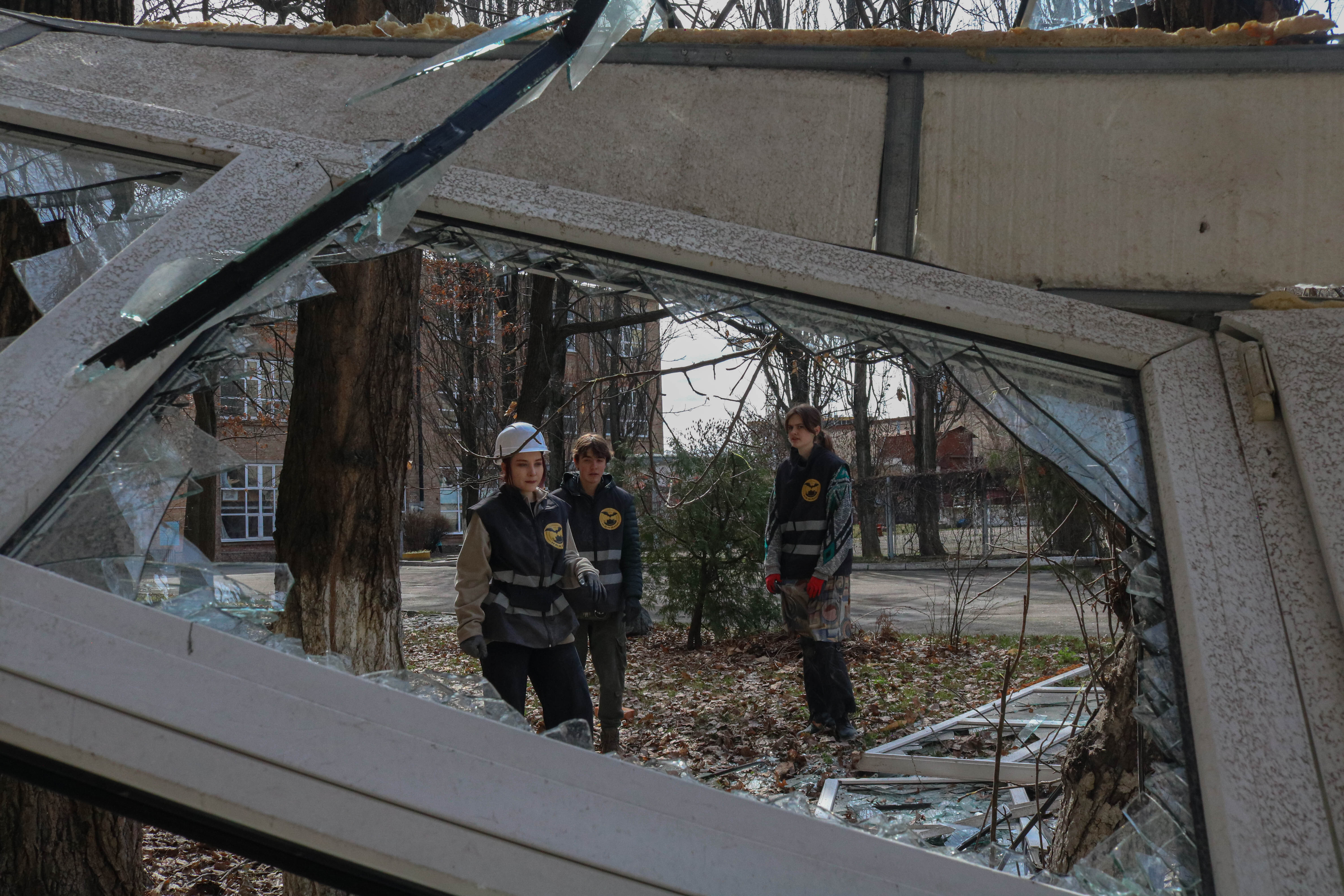 Framed by broken glass, citizens gather to pick up trash and debris in a park