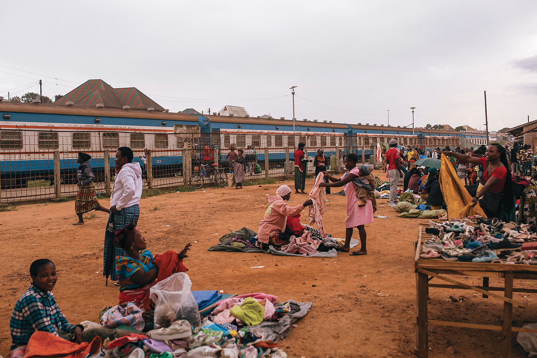Train passengers meander outside in a market area. 
