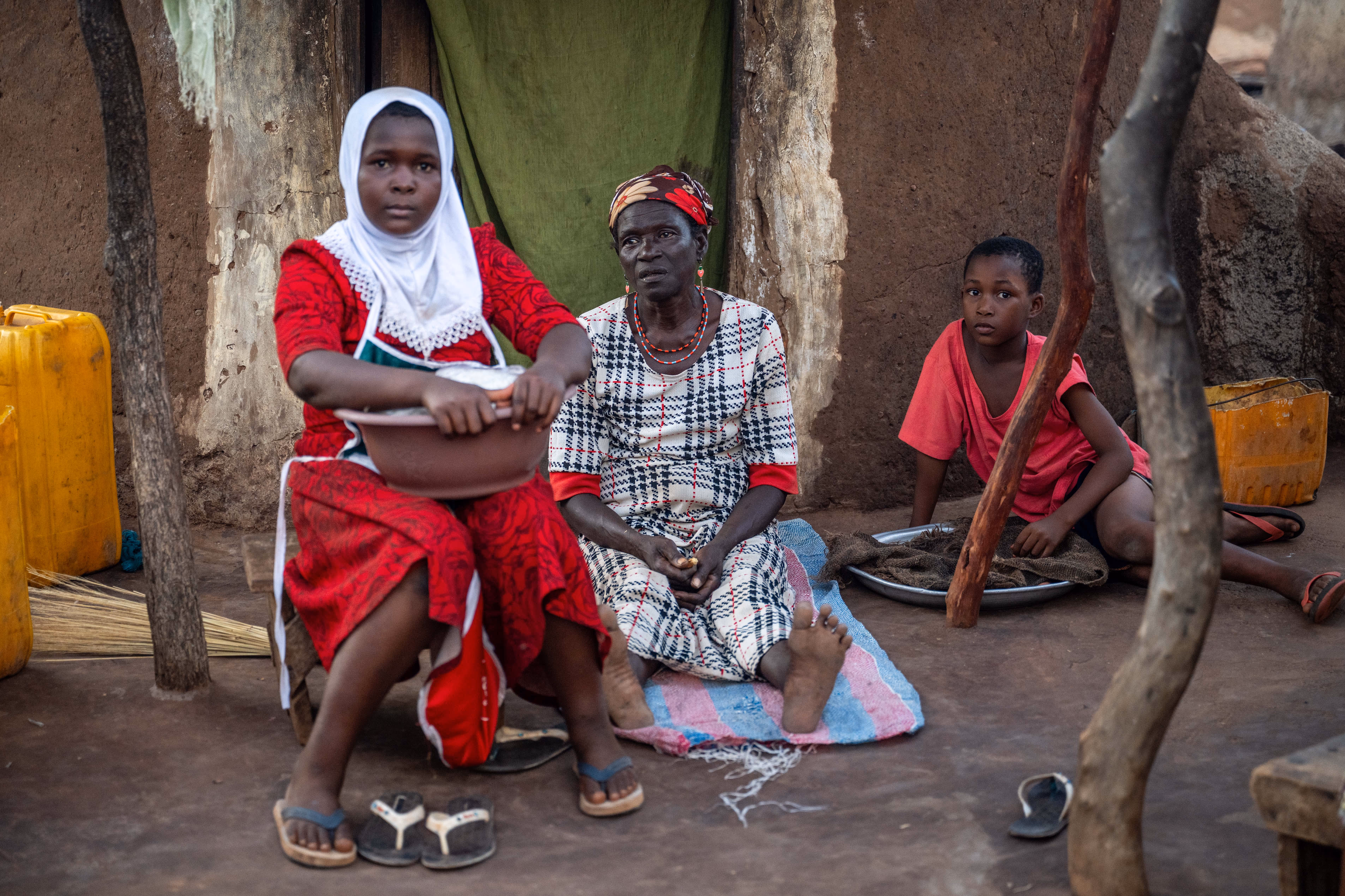 Two women and a young person sit in a row looking at the camera.