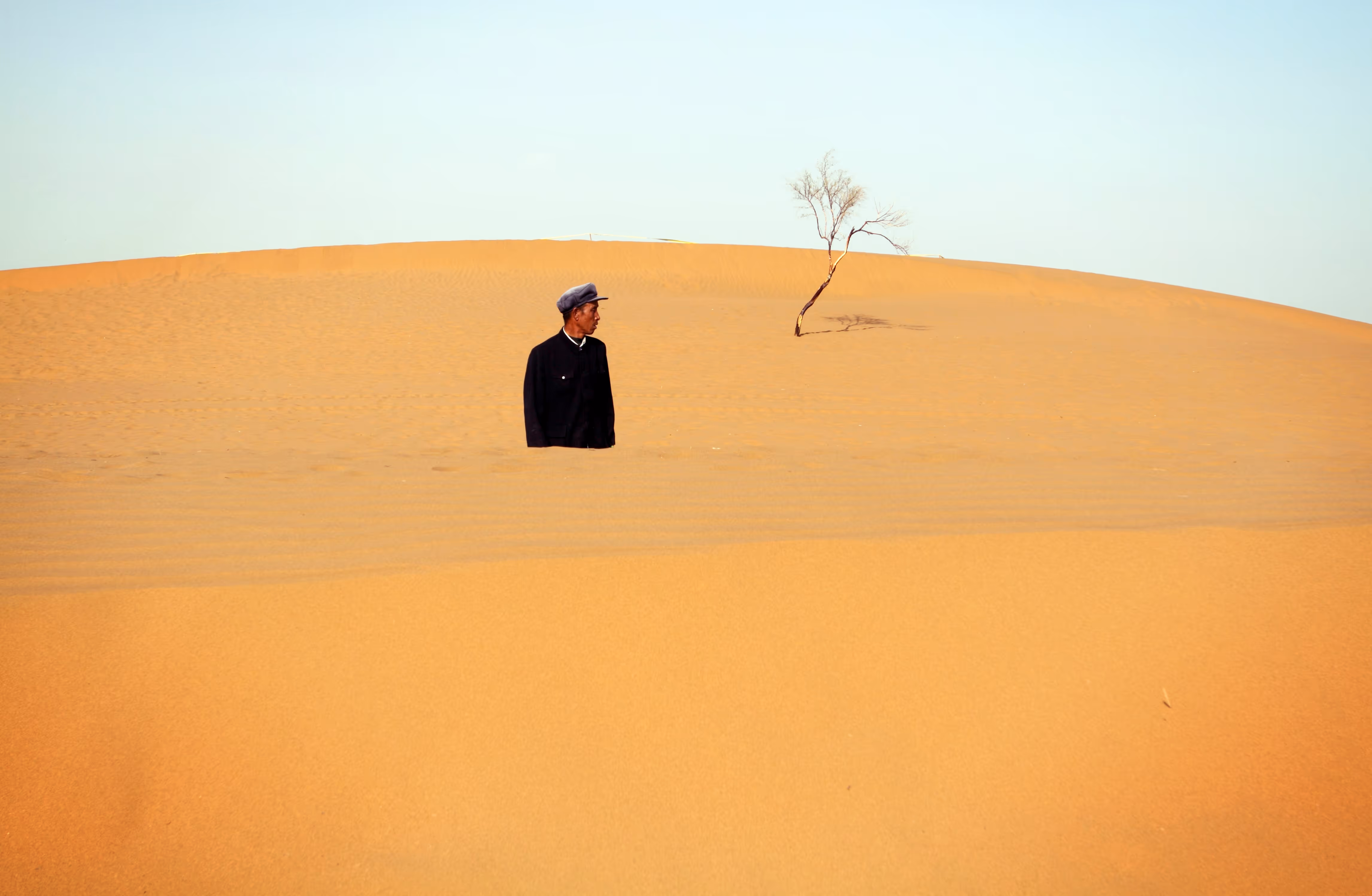 A man's body is cut off in the distance by rolling sand hills