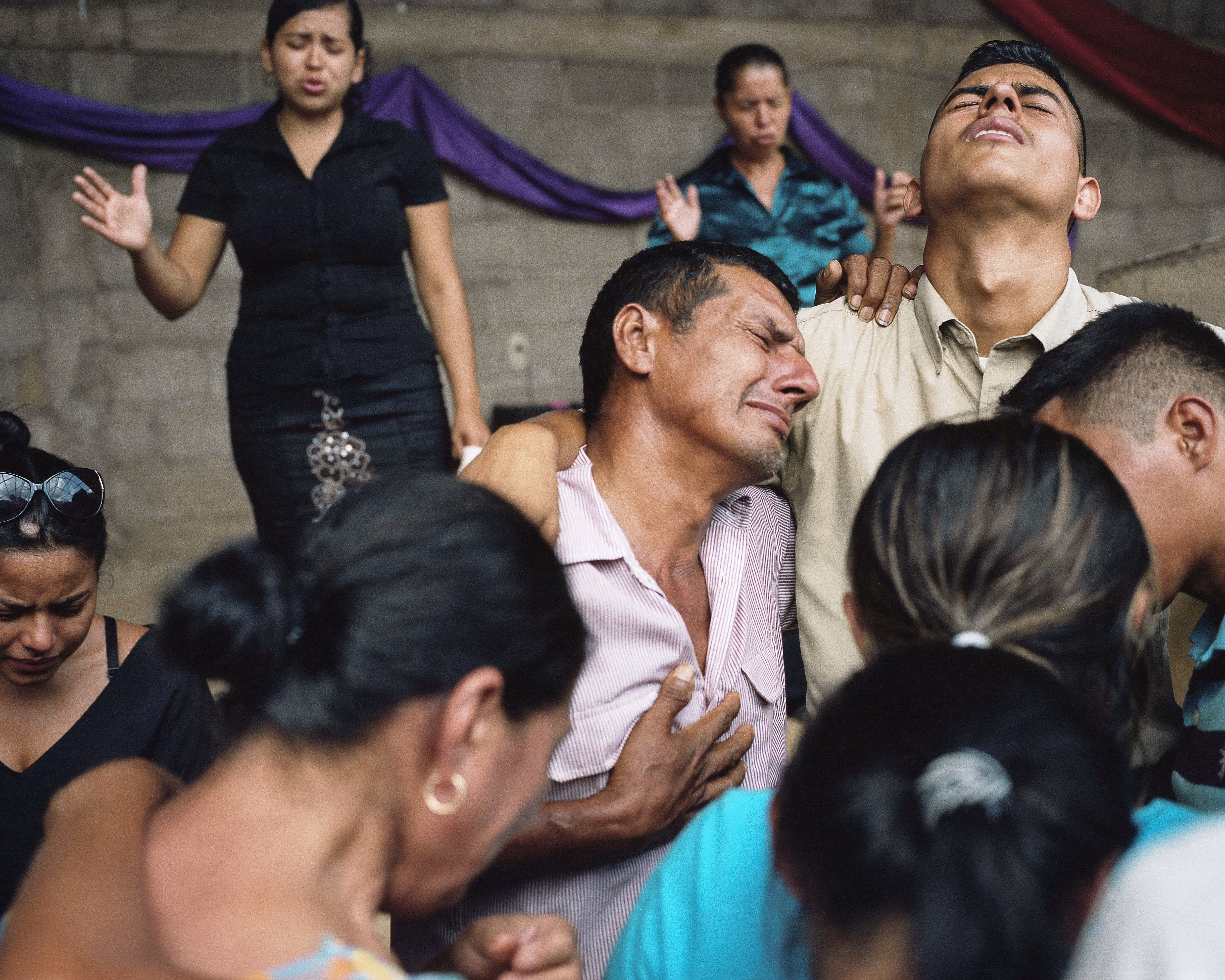 A group of people mourn together at a funeral