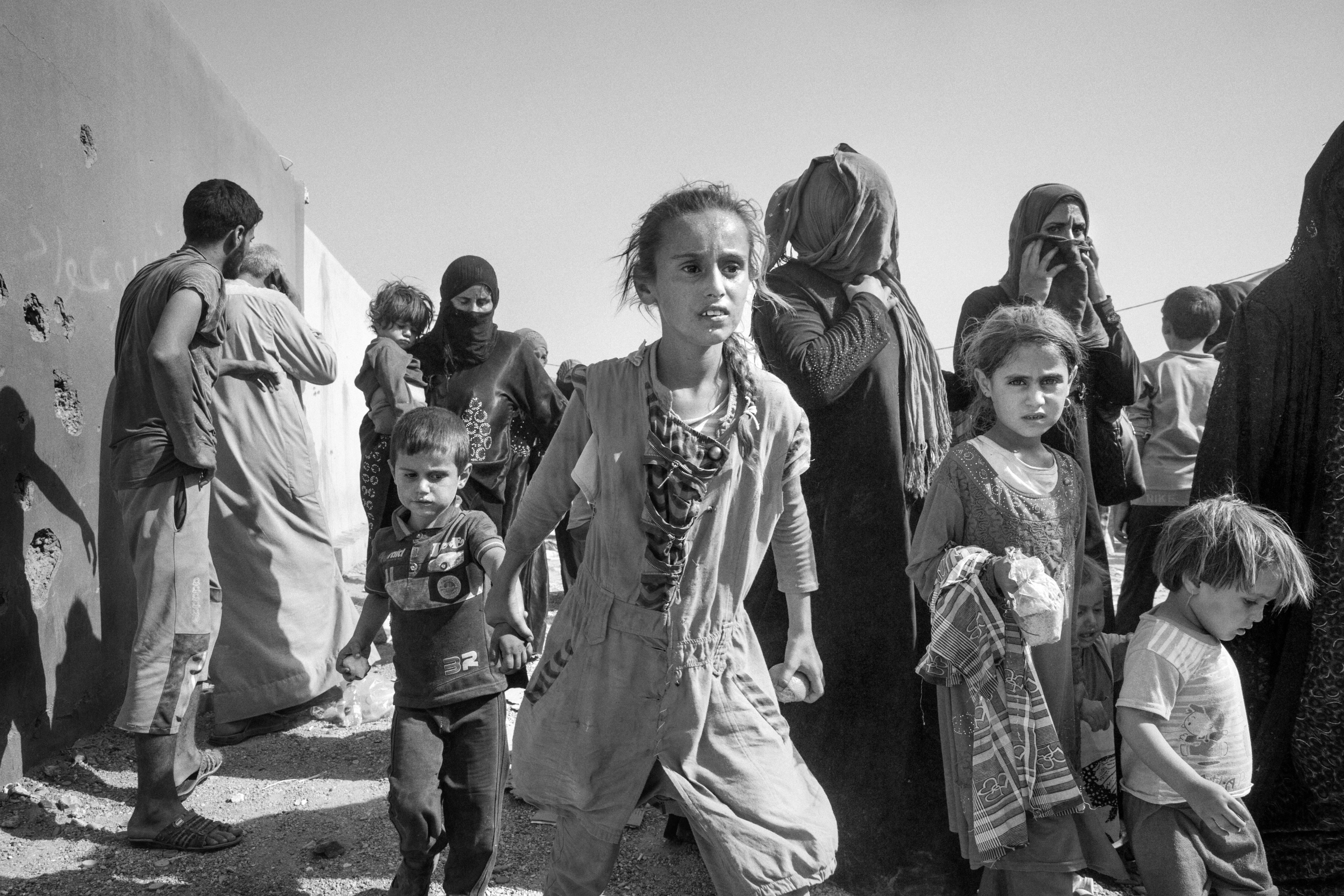 A group of young children look concerned as they walk in a crowd