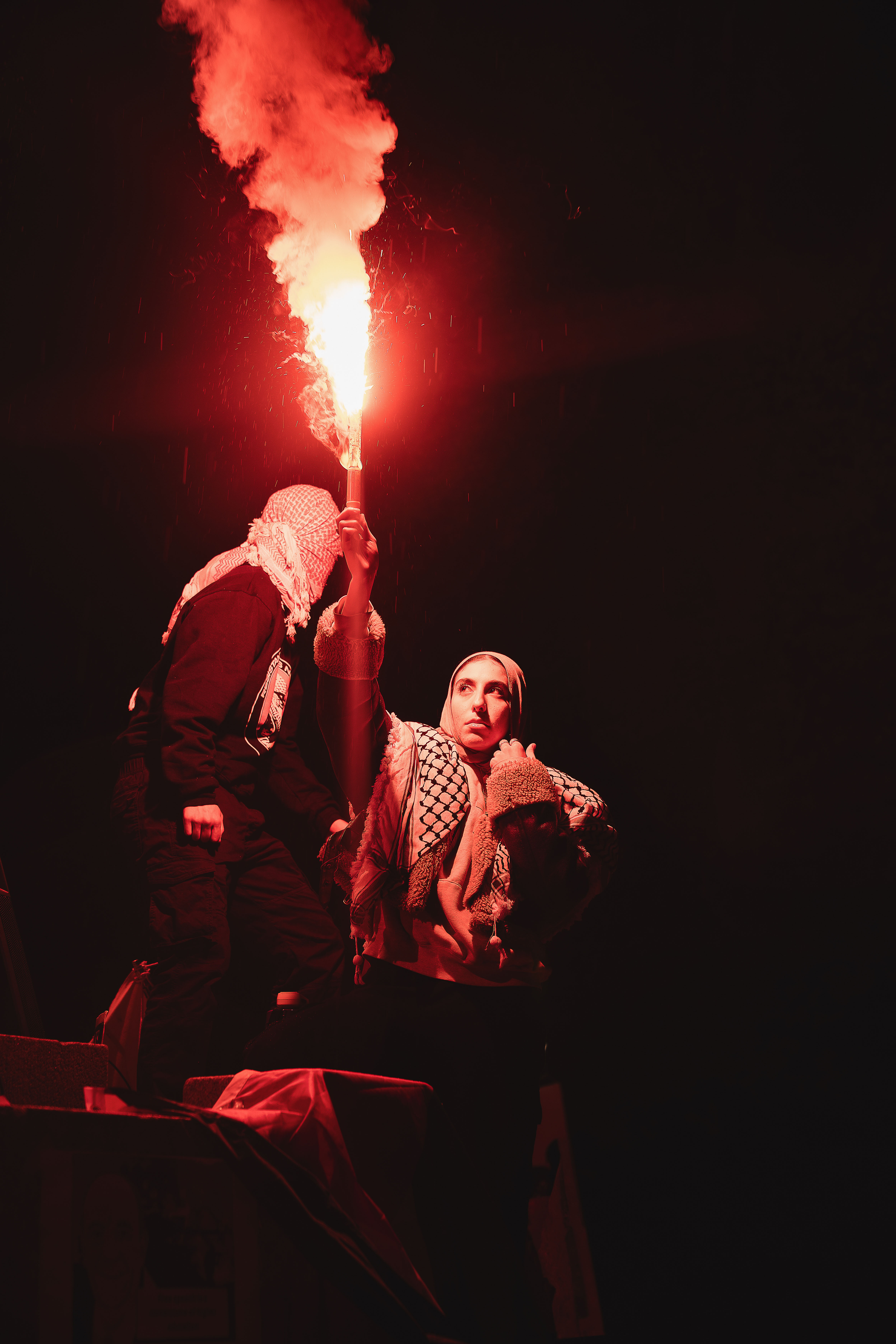 Protestors shoot off a bright red flare in the night