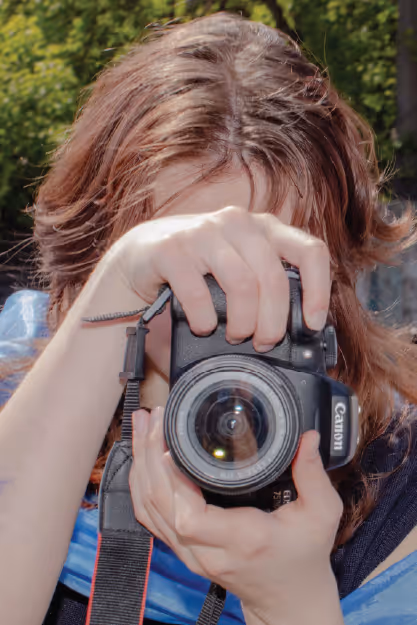 a young girl holds a camera up to her face