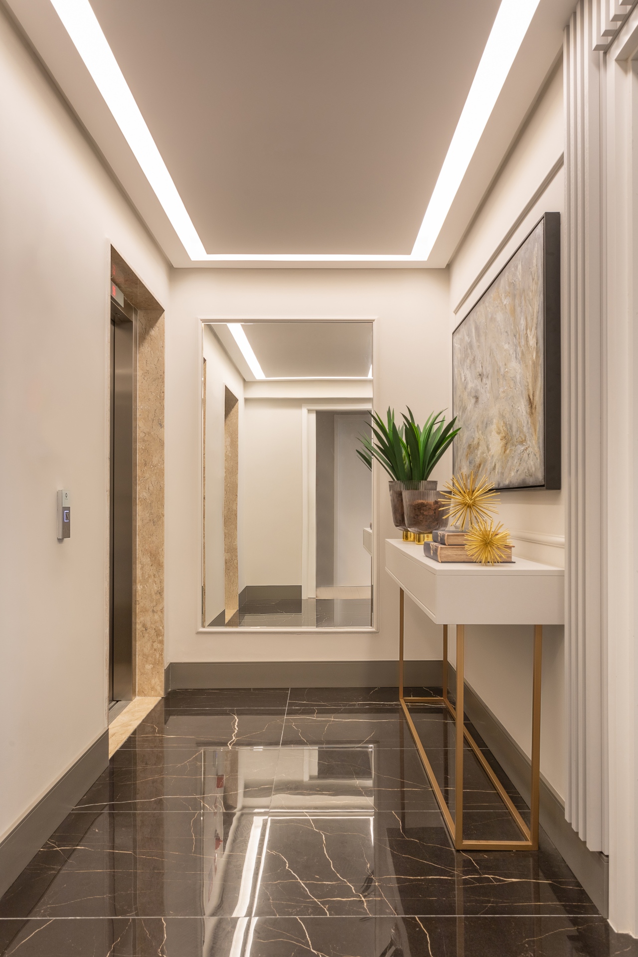 Hall de entrada com mármore, espelho, quadro e aparador branco com detalhes dourados