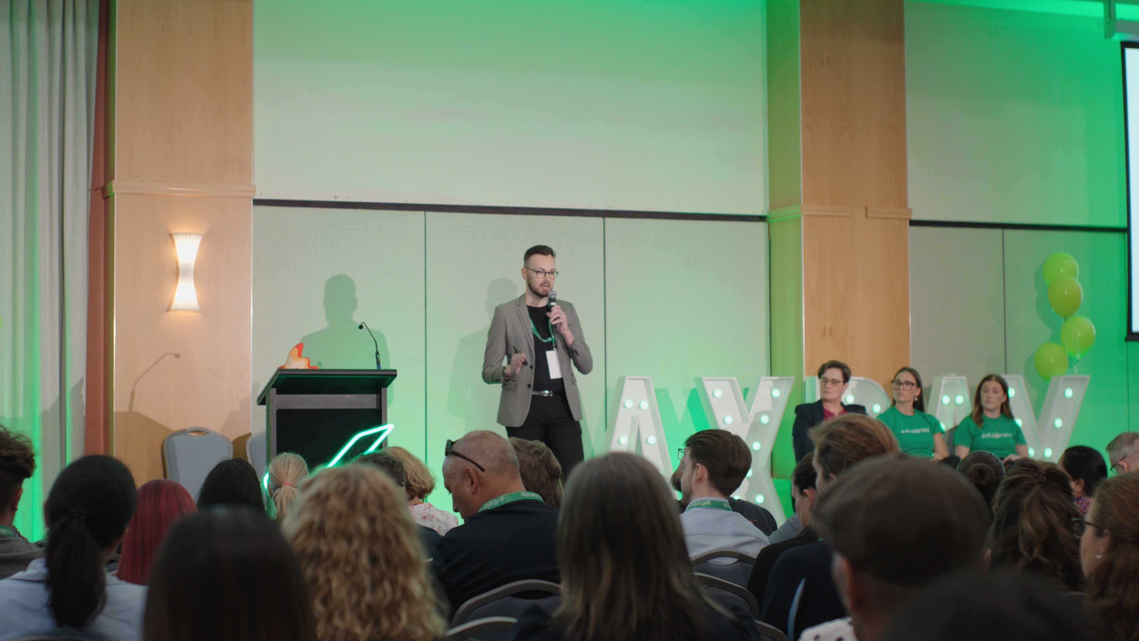 Marc Harris speaking on stage about AI at aXcelerate Day 2025