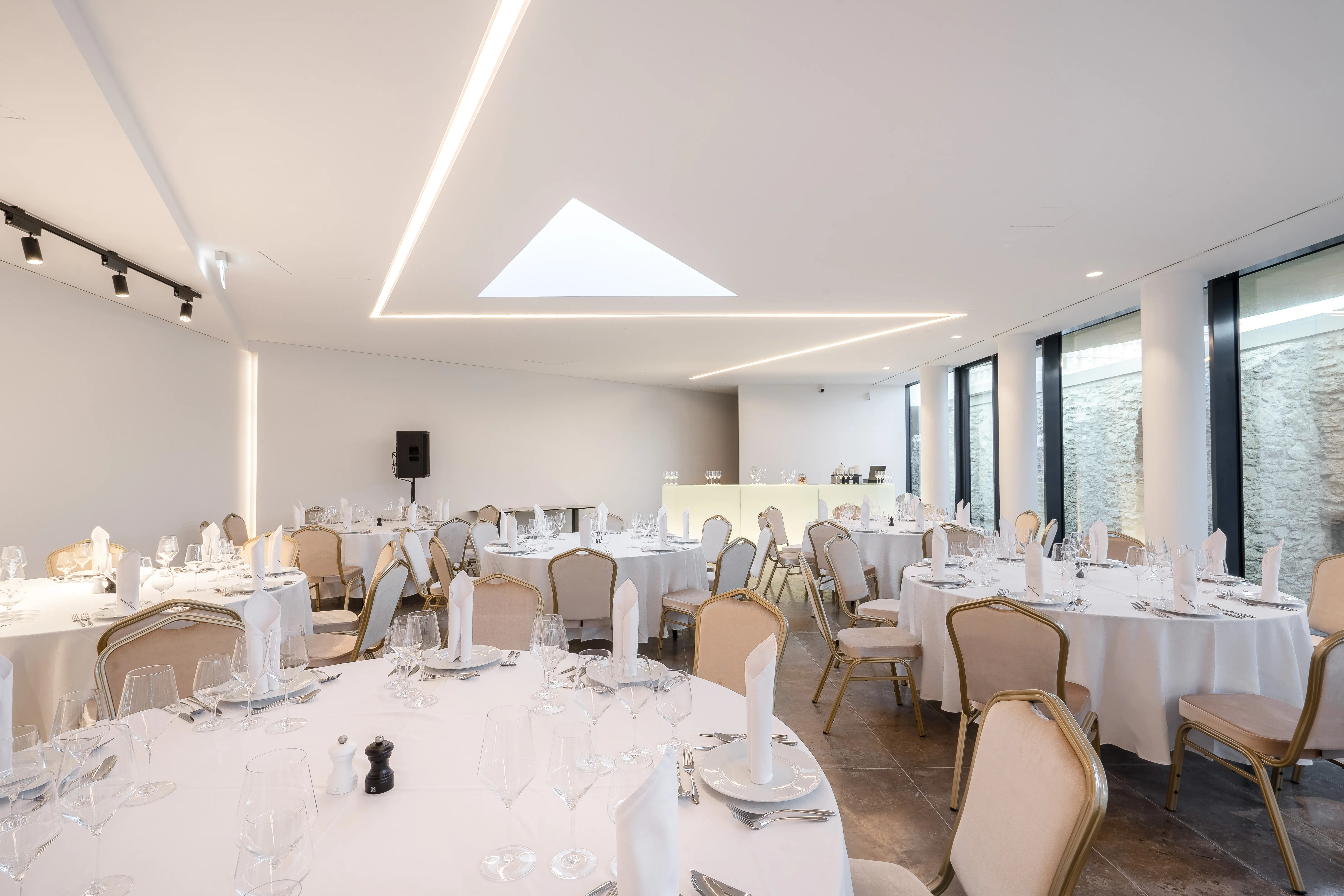 Egy nagy helyszín, amely asztalokkal és székekkel van szépen megtervezve egy esküvői eseményhez.