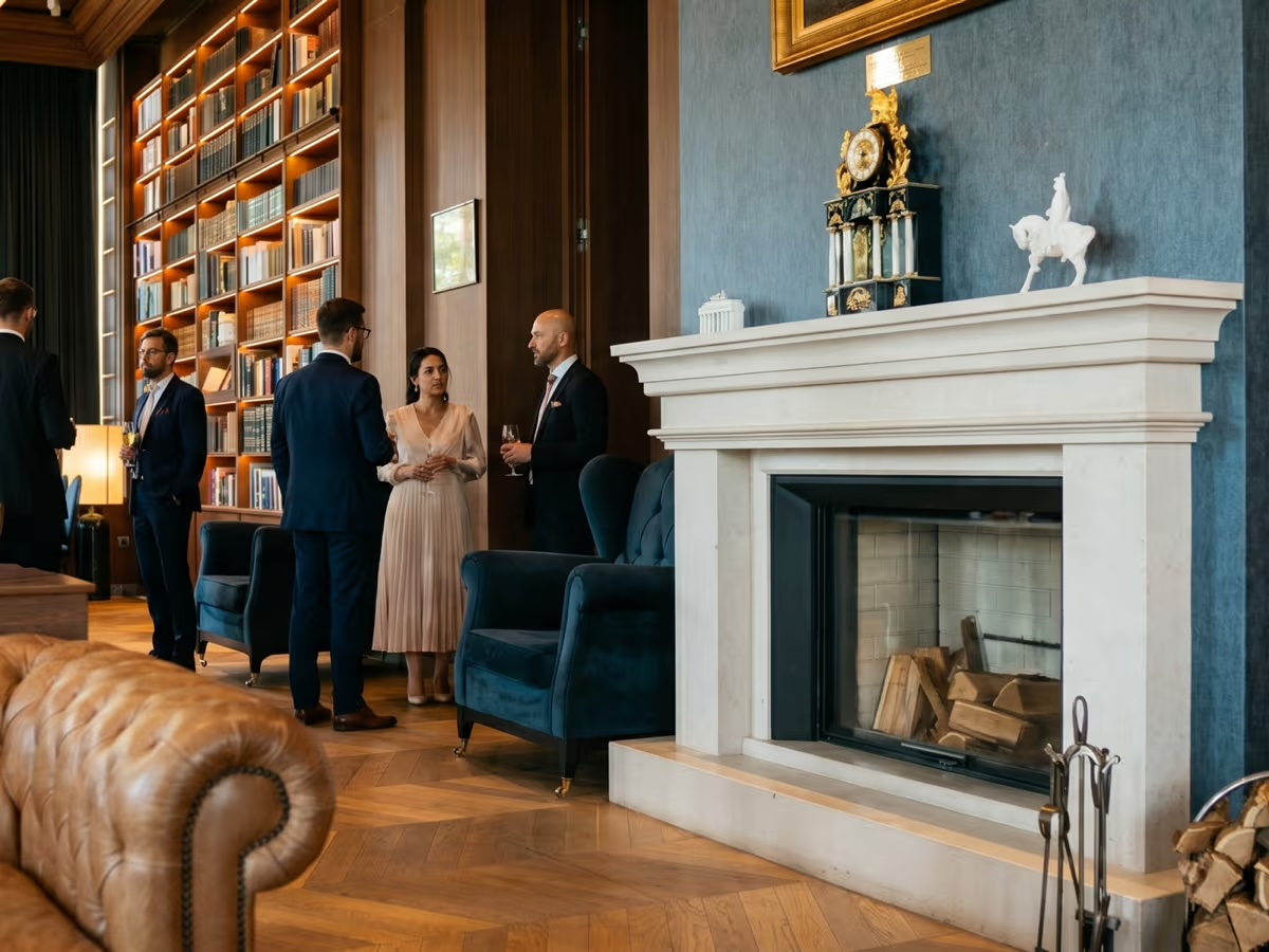 Guests chatting by the fireplace in the Library Room, surrounded by bookshelves that reach the ceiling