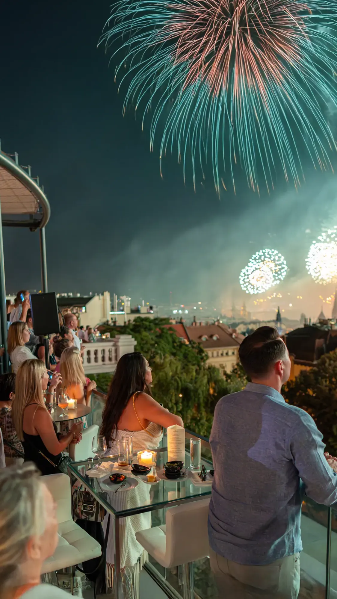 Fireworks over the Budapest skyline, viewed Aranybástya the Aranybástya, with champagne glasses in the foreground