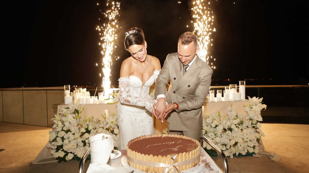 The young couple cuts their wedding cake on the terrace of the Aranybástya in the evening