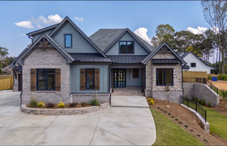 Two-story brick and wood house with three front gables and a driveway ending at the entrance.