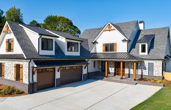 Modern two-story house with stone and white siding, wooden accents, two-car garage, and a concrete driveway.