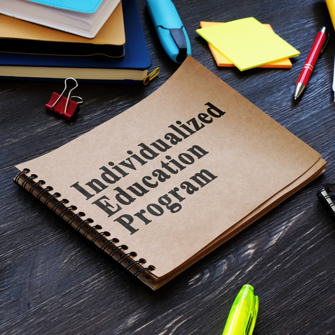 Spiral notebook labeled Individualized Education Program beside school supplies on a desk