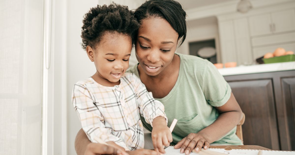Adult and young child practicing language with picture cards and letter blocks